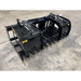 Black steel skid steer grapple attachment with dual hydraulic cylinders, curved tines, and reinforced frame on concrete floor