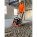 Worker operating orange and black MBW plate compactor smoothing loose soil inside unfinished building