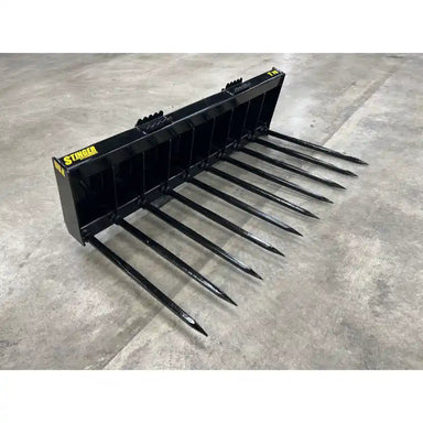 Angled right view of black steel manure spear attachment with multiple long pointed tines on concrete floor