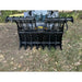 Front view of black steel clam grapple attachment with open jaws mounted on skid steer in outdoor setting