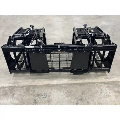 Black steel tractor root and rock grapple attachment with dual hydraulic cylinders and grid-style tines on concrete floor