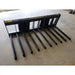 Black metal manure spear attachment with ten tubular tines and rectangular mounting frame on concrete floor indoors