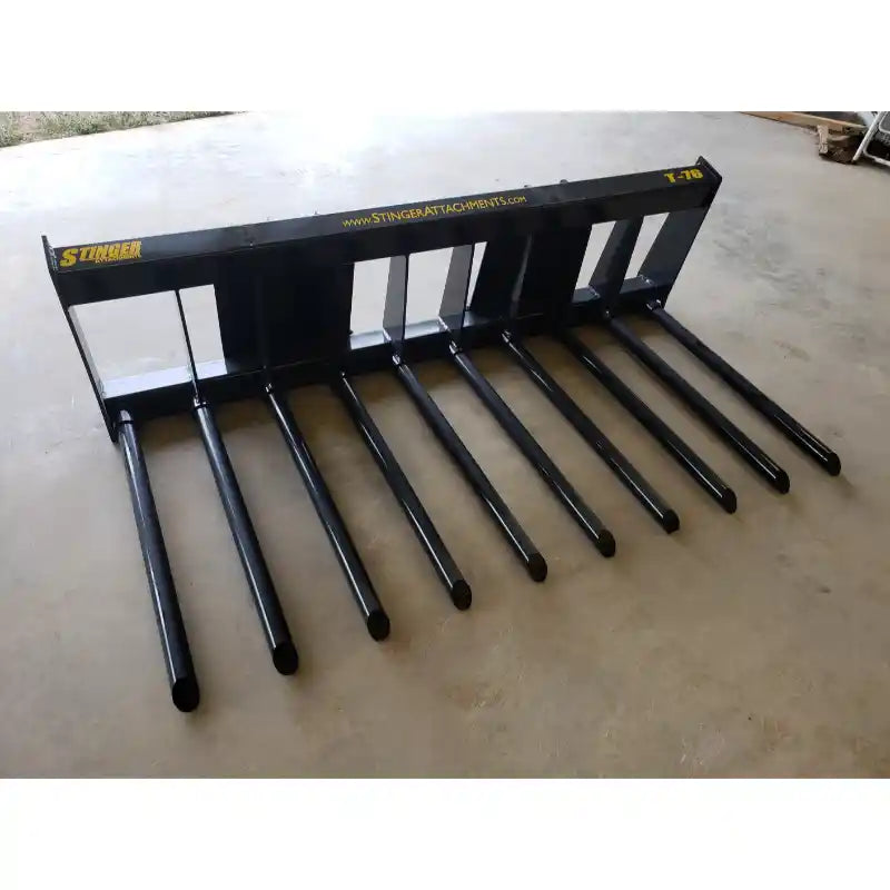 Black steel manure tine attachment with nine tubular tines and rectangular frame on concrete floor indoors
