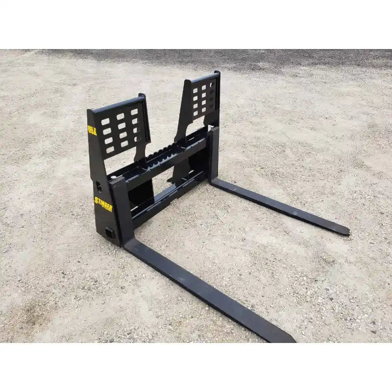Black steel pallet fork attachment with integrated backrest and weld reinforcements on gravel surface