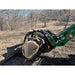 Green loader arm with black steel log grapple attachment holding large cut tree log on bare soil