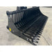 Black metal rock bucket attachment with narrow spaced curved tines and reinforced side panels on concrete floor