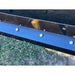 Close-up of blue steel cutting edge bolted to black snow pusher blade resting on grass surface