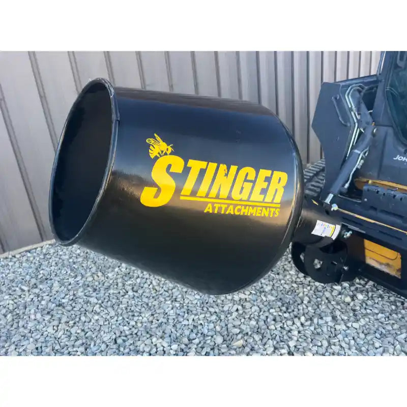 Black round concrete mixing drum attachment with yellow Stinger logo mounted on skid steer loader arm over gravel ground