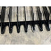Close-up of black metal bucket attachment with narrow spaced flat tines on concrete floor surface