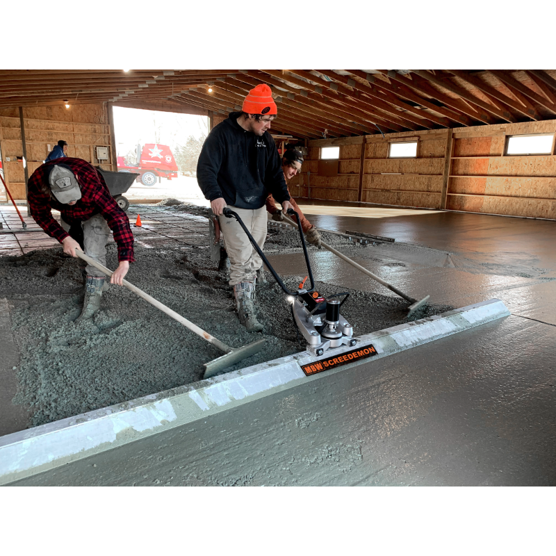 Three workers using MBW WS500 ScreeDemon vibratory wet screed to smooth freshly poured concrete indoors, gallery position 1