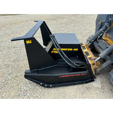 Black steel disc mulcher attachment with hydraulic hoses connected to skid steer on gravel surface