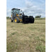 Yellow loader with black steel tractor grapple attachment featuring wide tines positioned on a grassy field