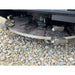 Close-up of underside steel rotary mulcher disc with cutting teeth and mounting bolts resting on gravel surface