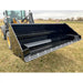 Front right view of black steel hydraulic tractor dump bucket attachment with reinforced cutting edge on grass field