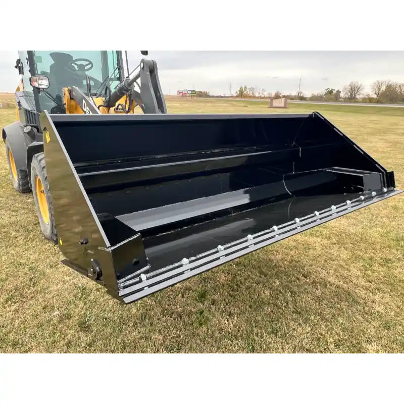 Front right view of black steel hydraulic tractor dump bucket attachment with reinforced cutting edge on grass field