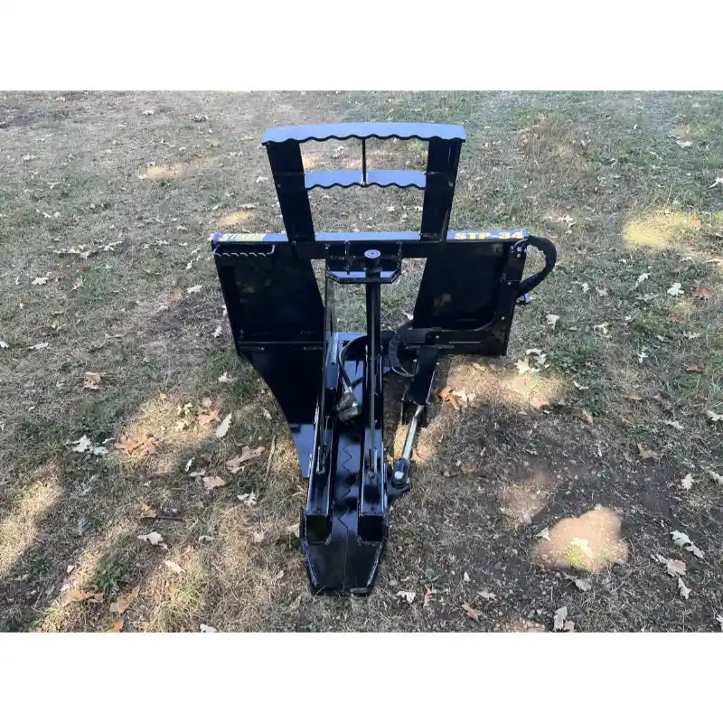 Black steel tree puller attachment with flat back plates, hydraulic arm, and reinforced frame on grass and dirt surface