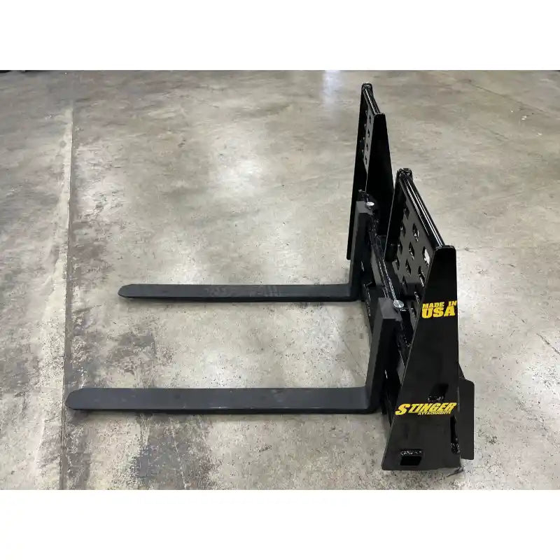 Black steel pallet forks with upright mounting plate and yellow Stinger and Made in USA labels on concrete floor