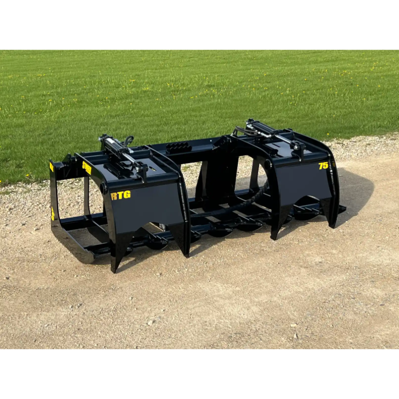 Black painted steel skid steer root grapple attachment with dual hydraulic cylinders and curved tines on gravel and grass background