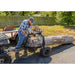 Man operating Swisher ATV log skidder with hand crank winch lifting large hardwood log, gallery position 1