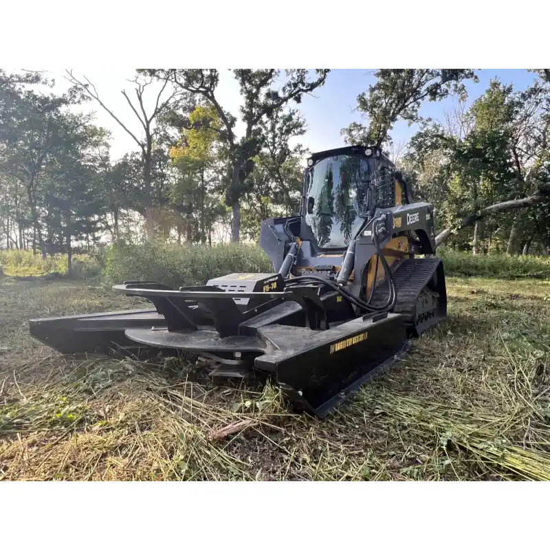 Skid steer brush cutter attachment with 1” pan, four blades, and open front design in outdoor wooded setting