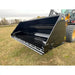 Black steel hydraulic dump bucket attachment with reinforced blade mounted on loader arm over grassy field