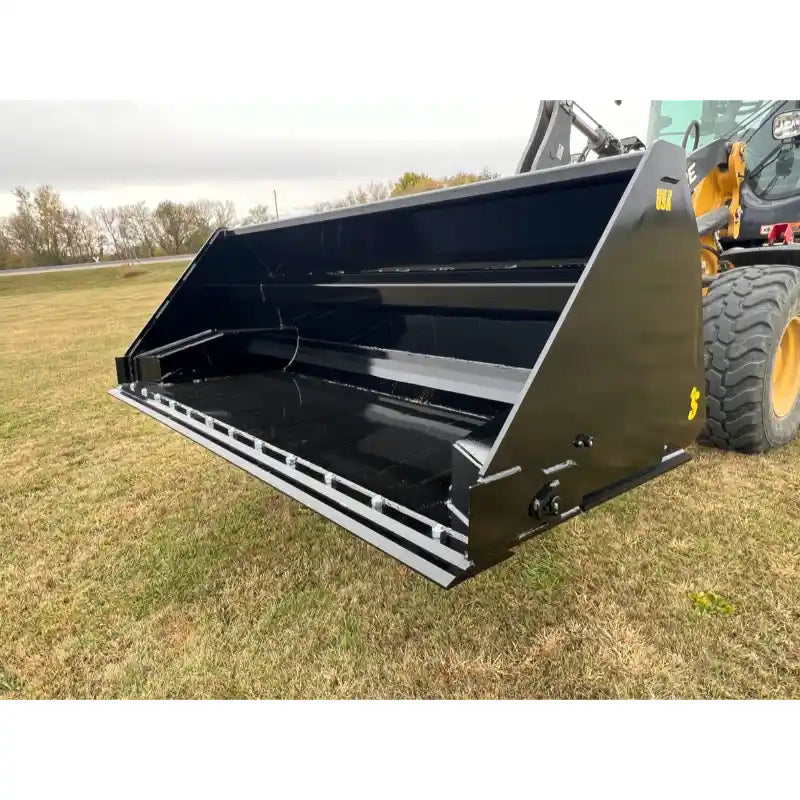 Black steel tractor hydraulic dump bucket attachment with reinforced blade mounted on loader arm over grass field