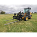 Yellow Deere skid steer with attached black pallet forks featuring solid backrest, parked on grassy field under cloudy sky