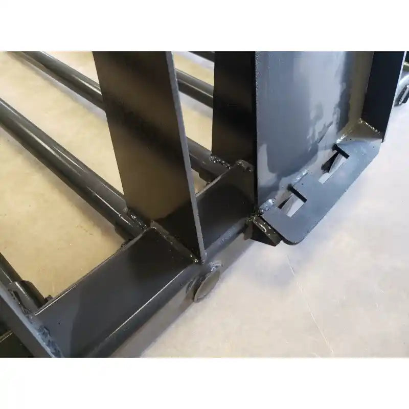 Close-up of black painted steel manure tine bucket attachment welds and tubular tine frame on concrete floor