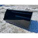 Front-left view of black steel skid steer bucket attachment resting on snow-dusted ground outdoors
