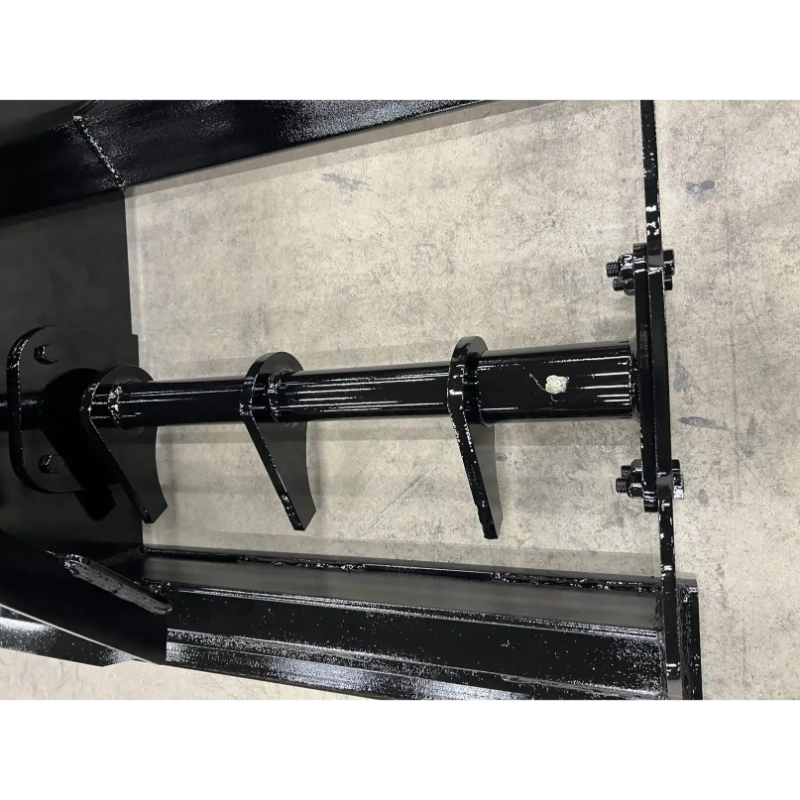 Close-up of black steel auger shaft with welded teeth and mounting brackets on concrete floor surface