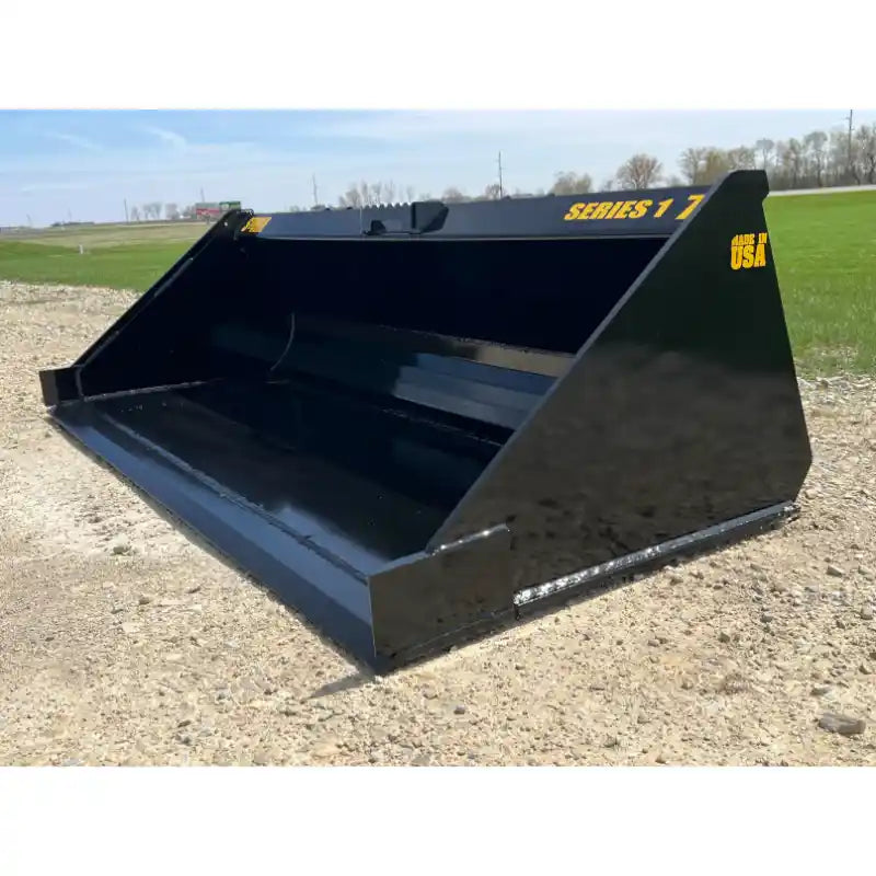 Left side view of black steel skid steer bucket attachment with smooth interior and yellow "Series 1 7" lettering outdoors