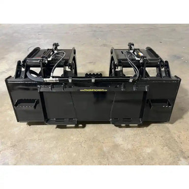 Black steel demolition grapple attachment with dual hydraulic arms on concrete floor in warehouse setting