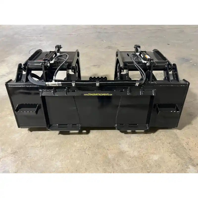 Black steel demolition grapple attachment with dual hydraulic arms on concrete floor in warehouse setting