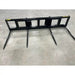 Black steel skid steer attachment with four tapered pointed steel tines on concrete floor viewed from front angle