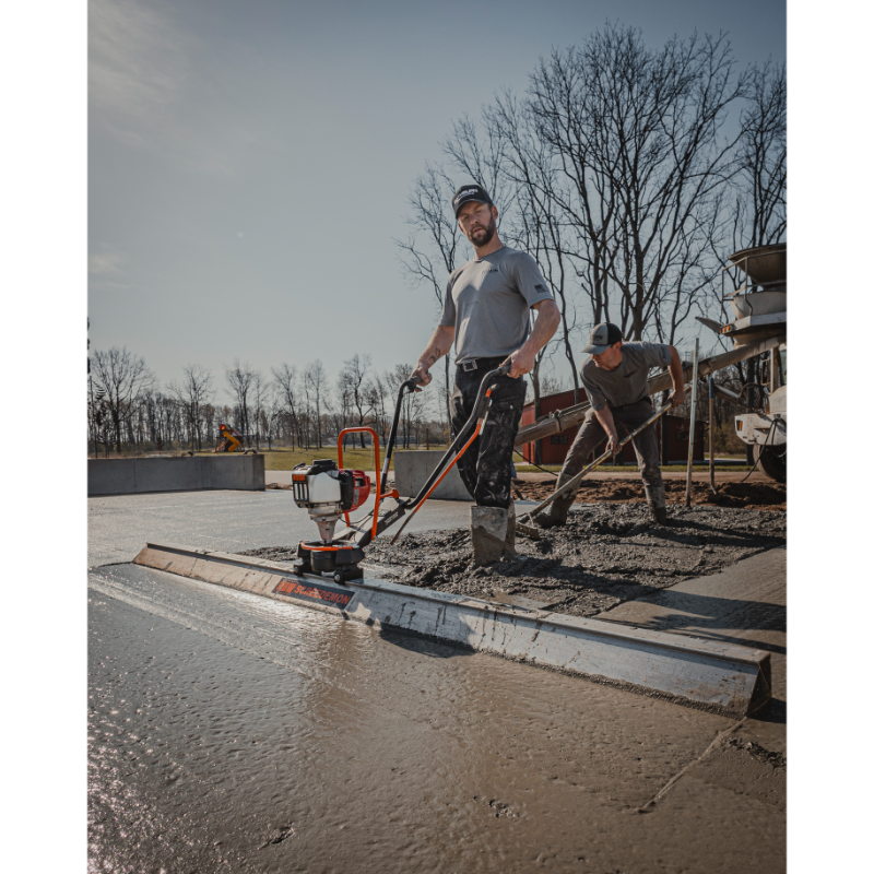 Operator using MBW 501H ScreeDemon gas-powered vibratory wet screed to level freshly poured concrete, gallery position 1