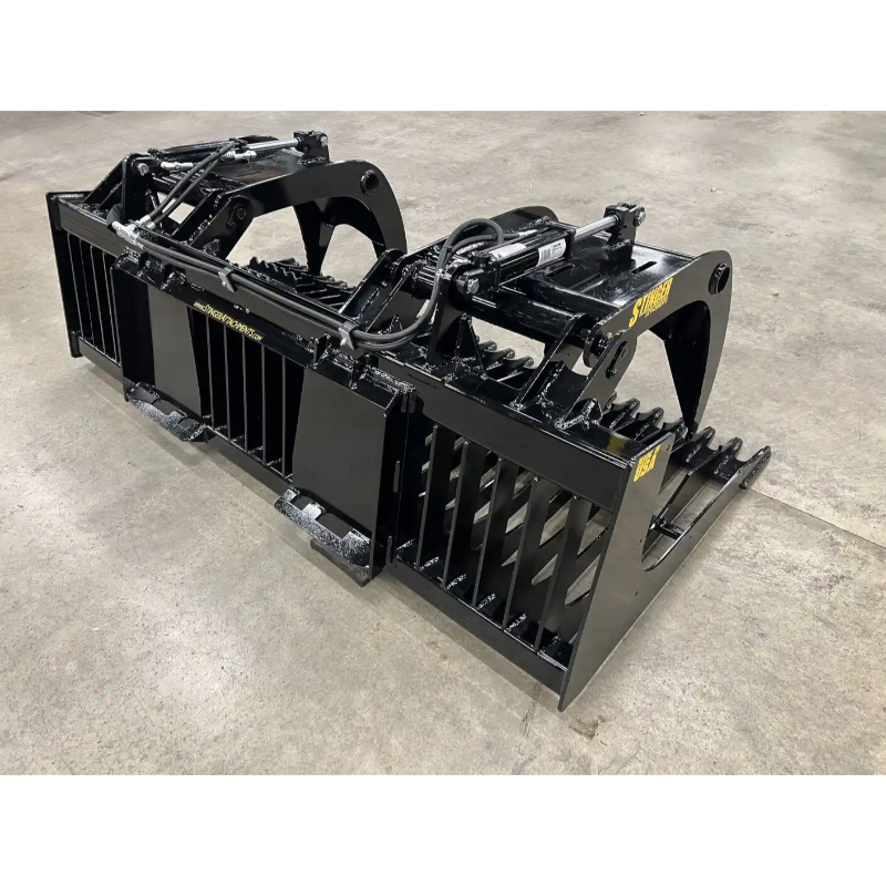 Black painted steel skid steer rock grapple attachment featuring hydraulic cylinders and serrated tines on concrete floor