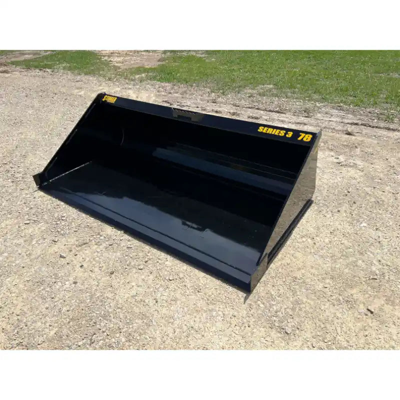 Black skid steer material bucket with flat bottom, reinforced edges, and yellow Series 3 78 markings on gravel surface