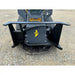 Black steel skid steer attachment with hydraulic hoses and yellow logo mounted on compact track loader on gravel surface