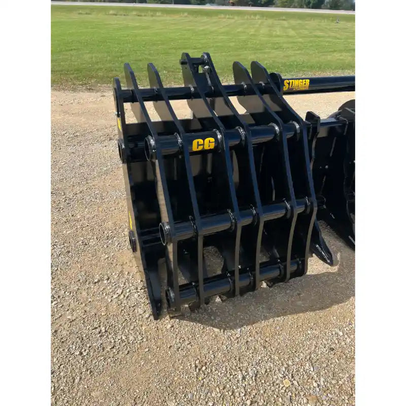 Black steel clam grapple attachment with multiple curved tines and a reinforced frame on gravel surface outdoors