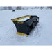 Back left angle of black and yellow skid steer snow pusher attachment resting on snow-covered ground outdoors