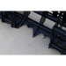 Close-up of black steel grapple attachment teeth and frame resting on concrete surface outdoors