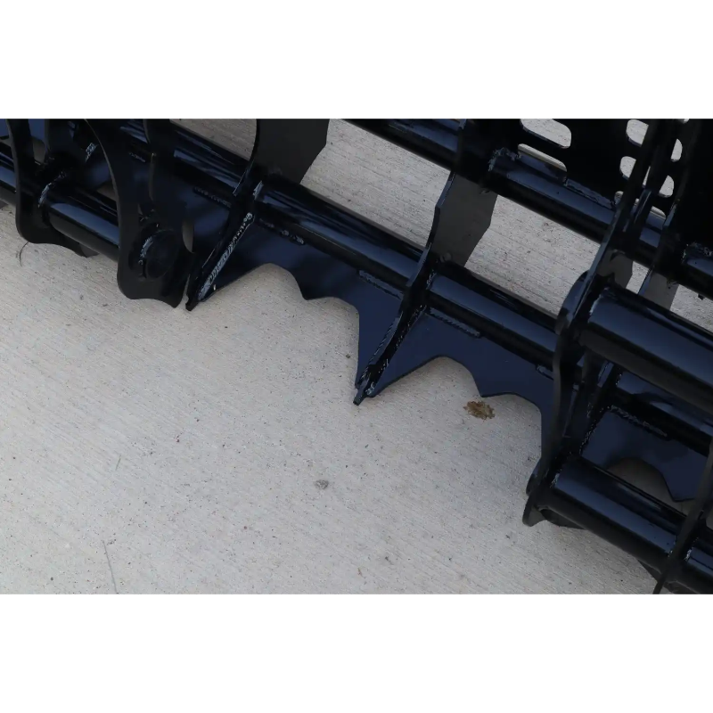 Close-up of black steel grapple attachment teeth and frame resting on concrete surface outdoors