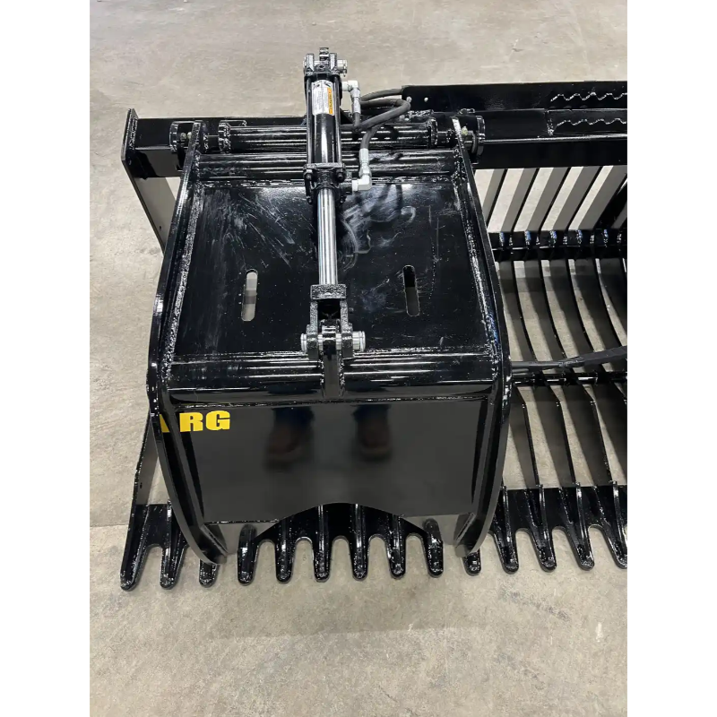 Close-up of black steel rock grapple attachment with hydraulic cylinder and curved tines on concrete floor