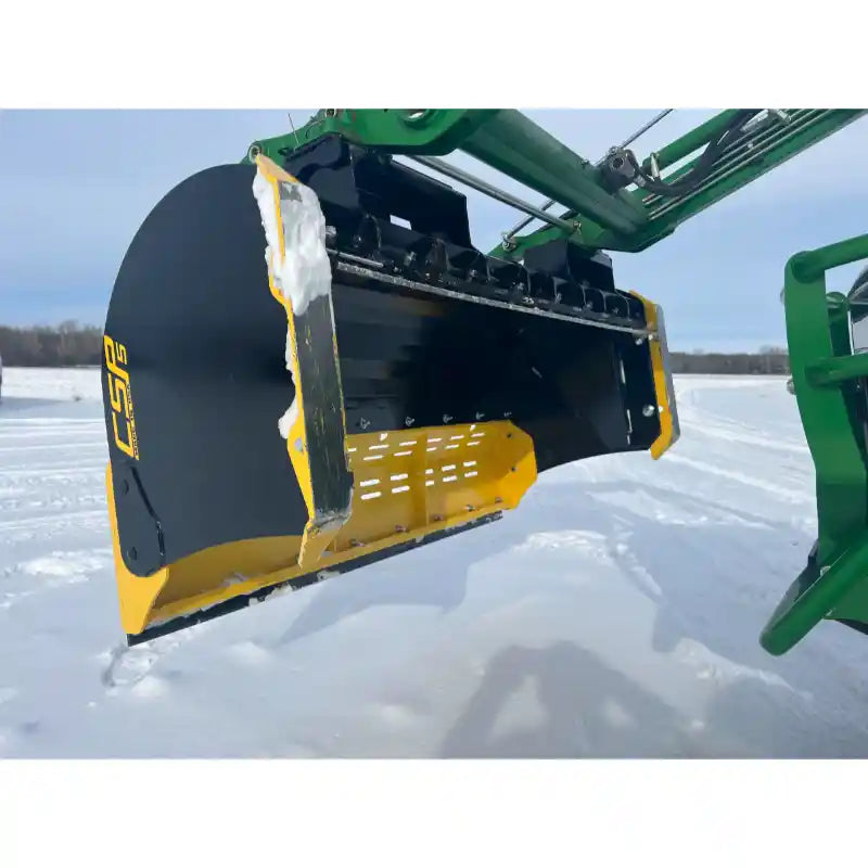 Black and yellow steel snow pusher attachment mounted on green loader arm over snowy ground with some snow on blade edges