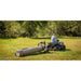 Rear view of ATV towing Swisher log skidder dragging large timber across grassy field, gallery position 1