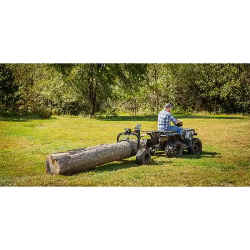 Rear view of ATV towing Swisher log skidder dragging large timber across grassy field, gallery position 1