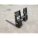 Black painted steel pallet fork attachment with reinforced vertical backrest and two long tines on gravel surface
