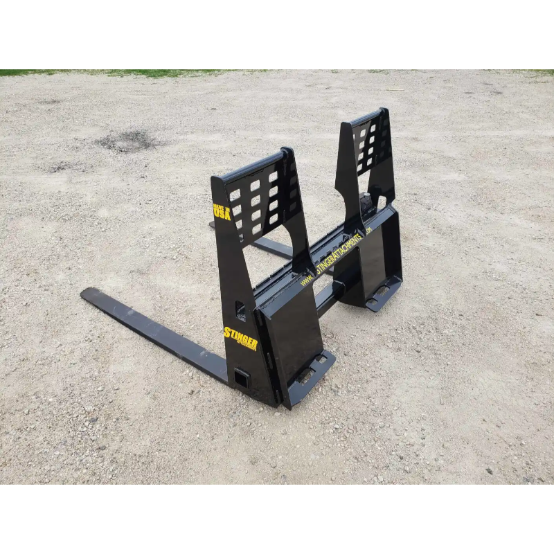 Black painted steel pallet fork attachment with reinforced vertical backrest and two long tines on gravel surface