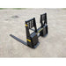 Black steel pallet fork attachment with vented backrest and dual fork arms on compacted gravel surface