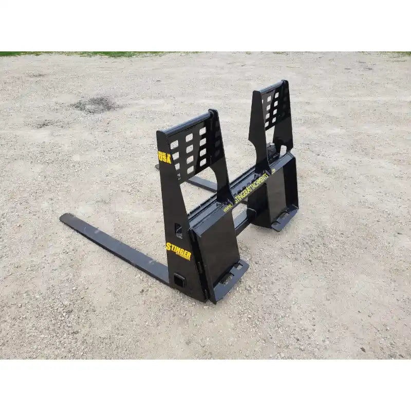 Black steel pallet fork attachment with vented backrest and dual fork arms on compacted gravel surface